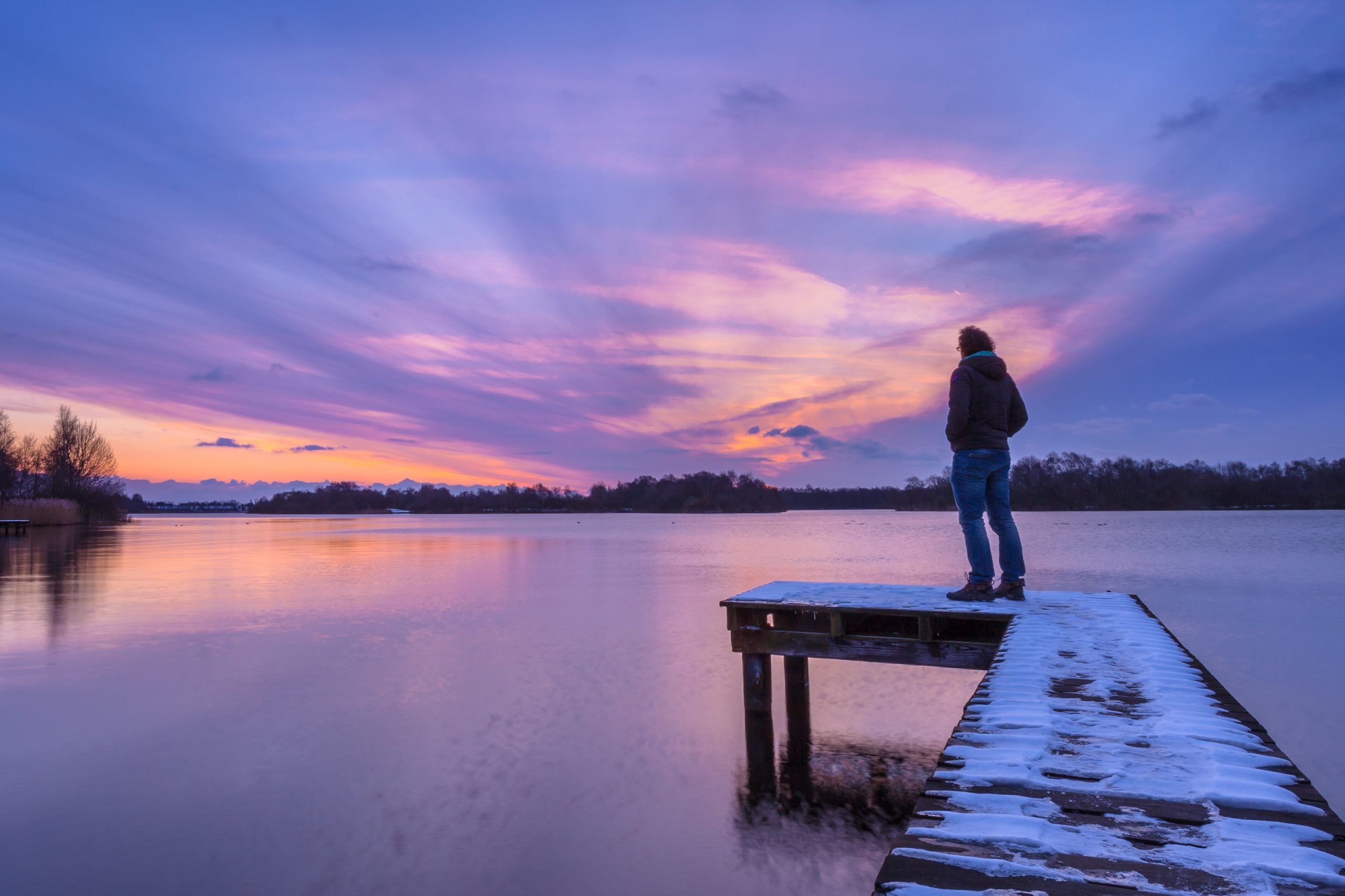 Man overthinking problems on pier during beautiful sunset in winter