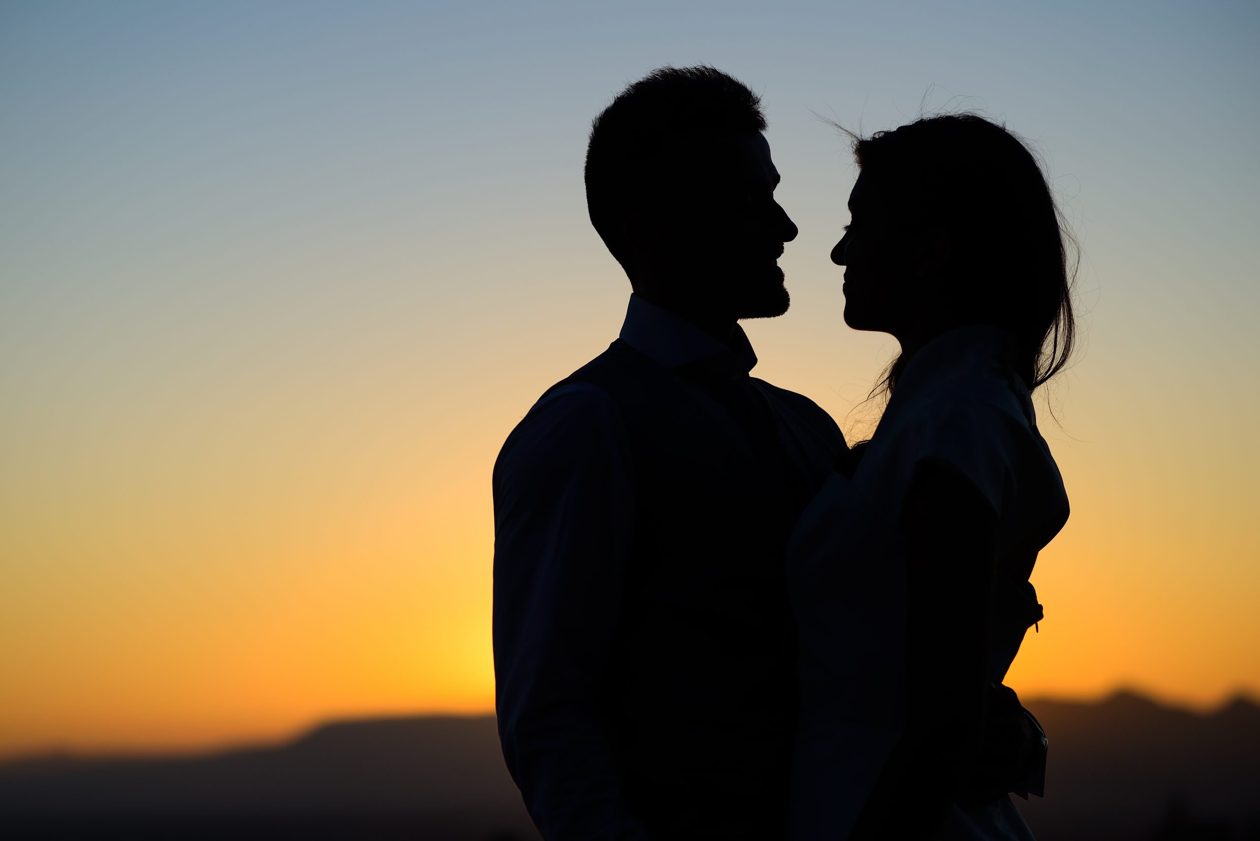 Silhouette of a young bride and groom on Sunset background