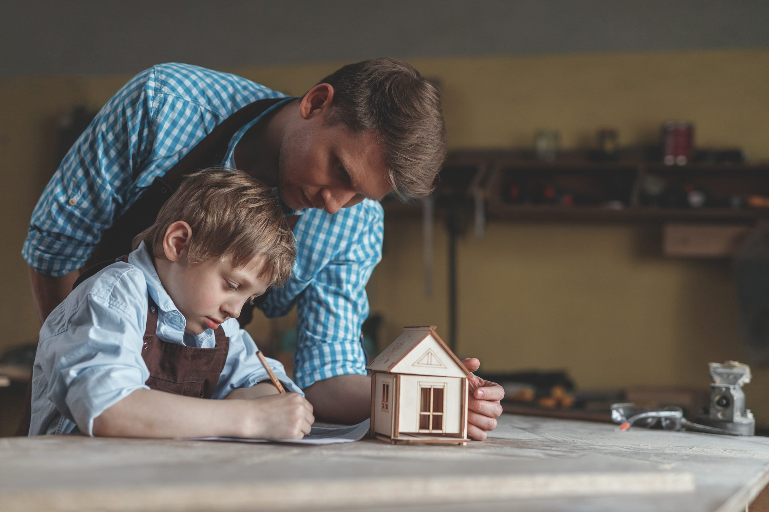 Father and son with a wooden house in the workshop