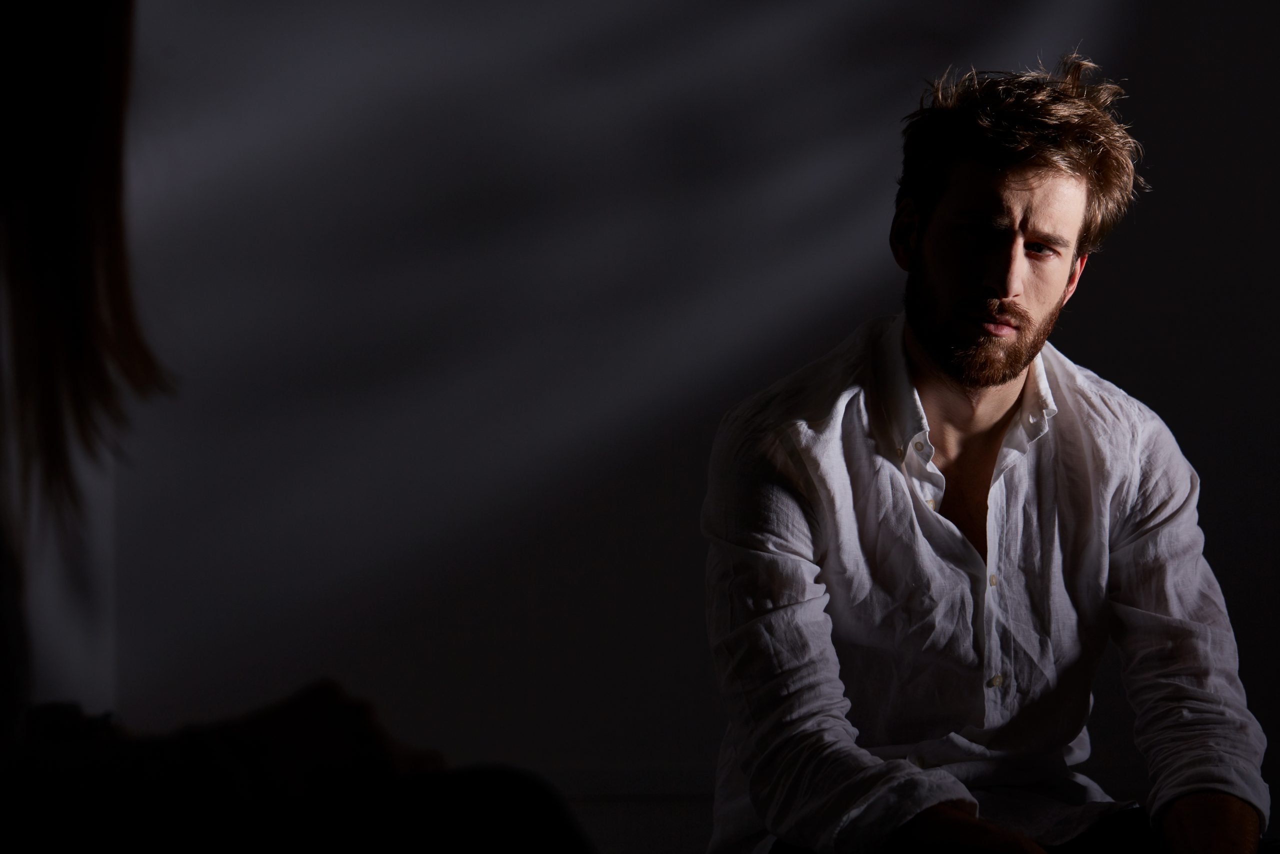 Depressed and thoughtful man sitting alone in dark room