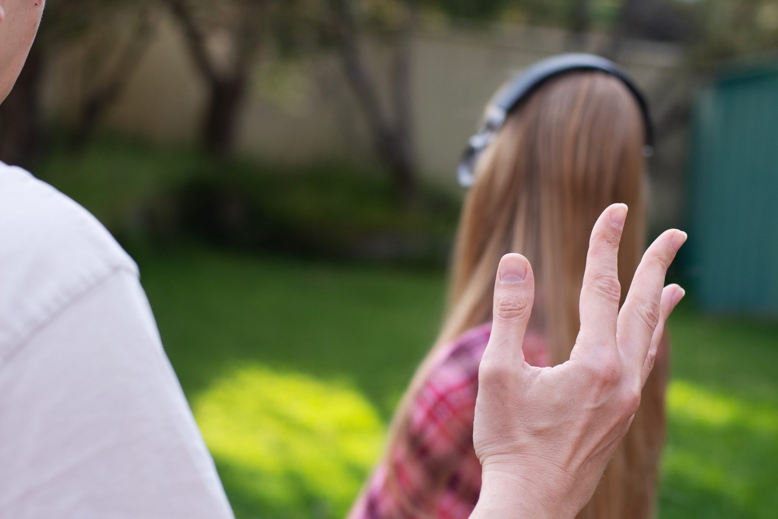 Problems between generations concept. Father argue with teenage daughter who is ignoring him. She wearing headphones and turned apart from him.