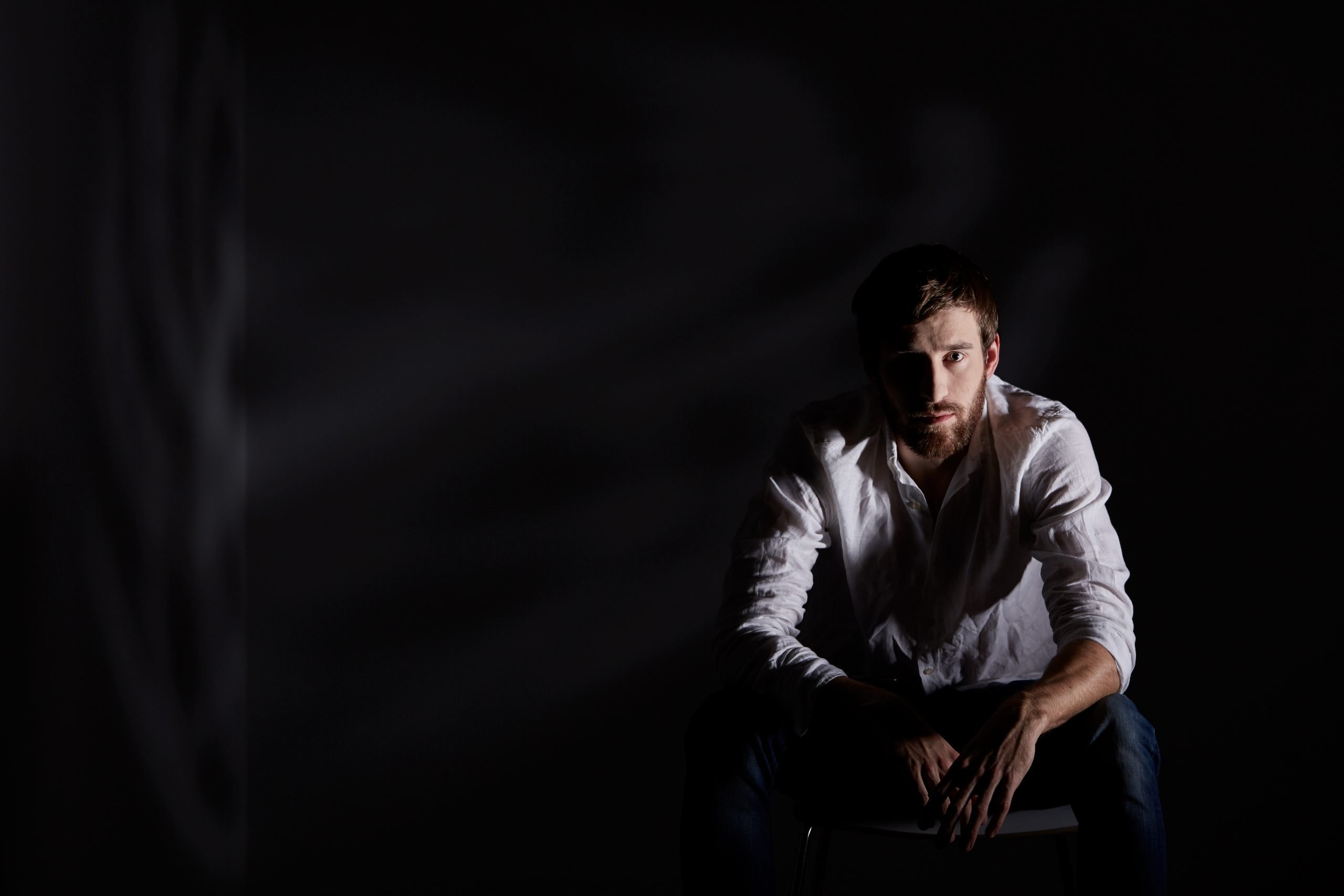 Desperate man sitting alone in dark room