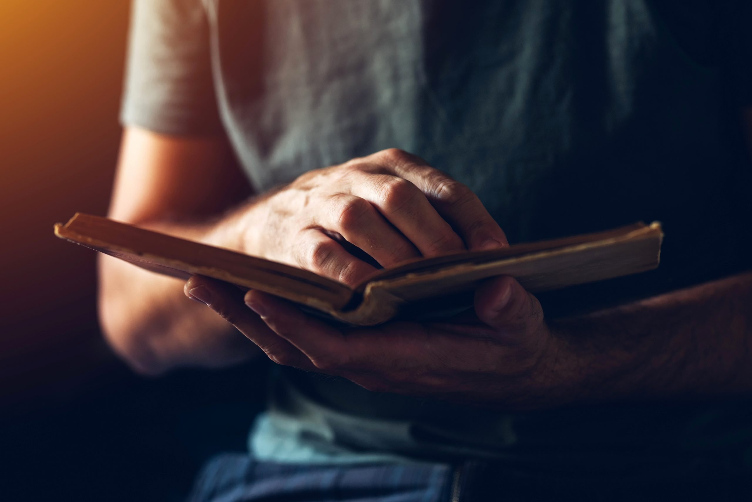 Reading an old book, close up of male hands flipping vintage weathered book pages