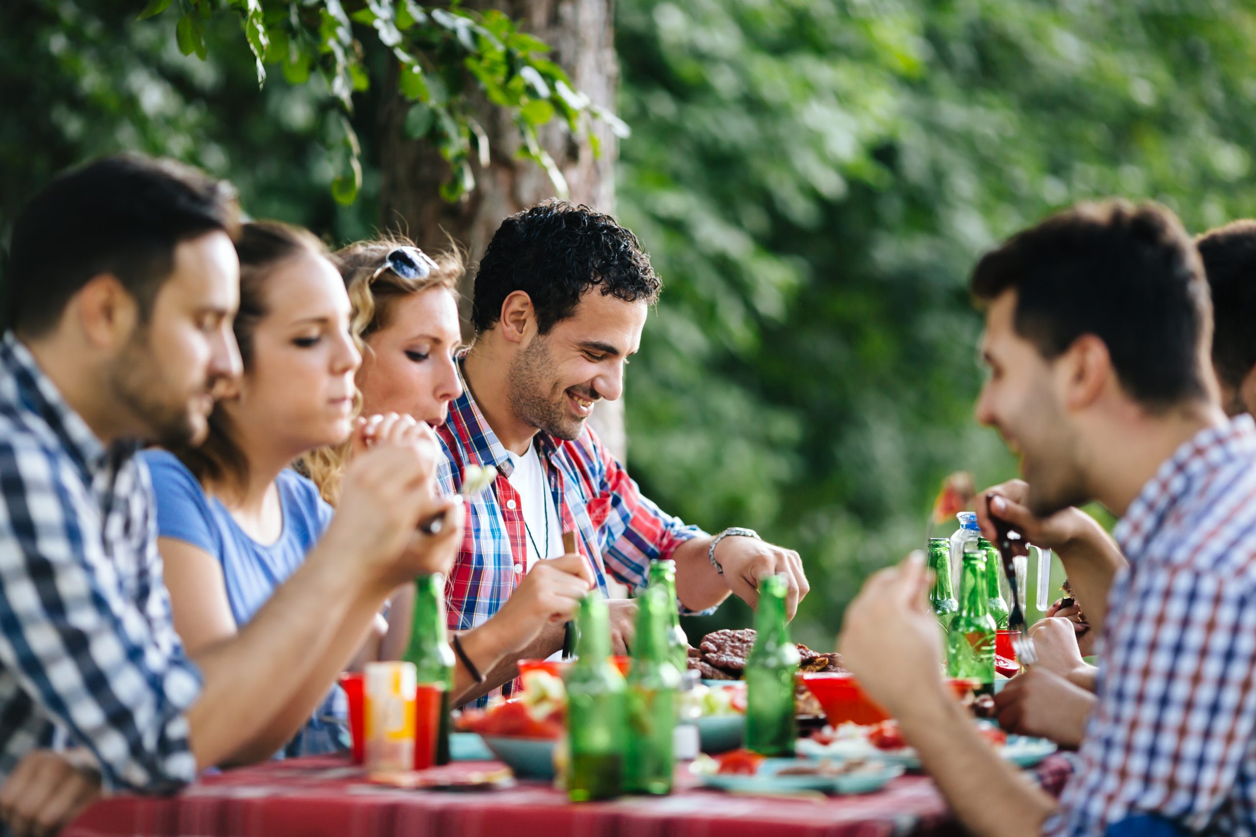 Friends eating outdoors and having fun after barbecuing