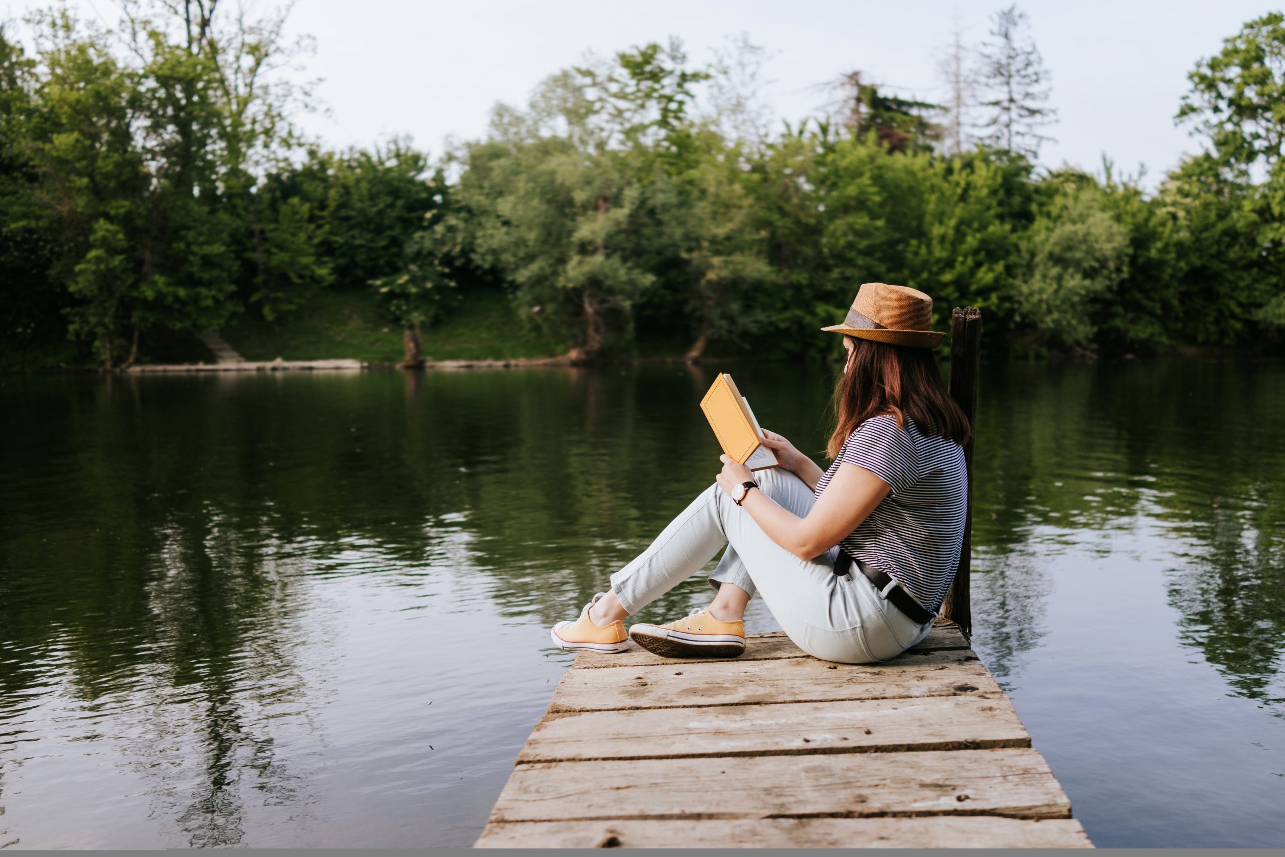 Young woman on the river pier reading book