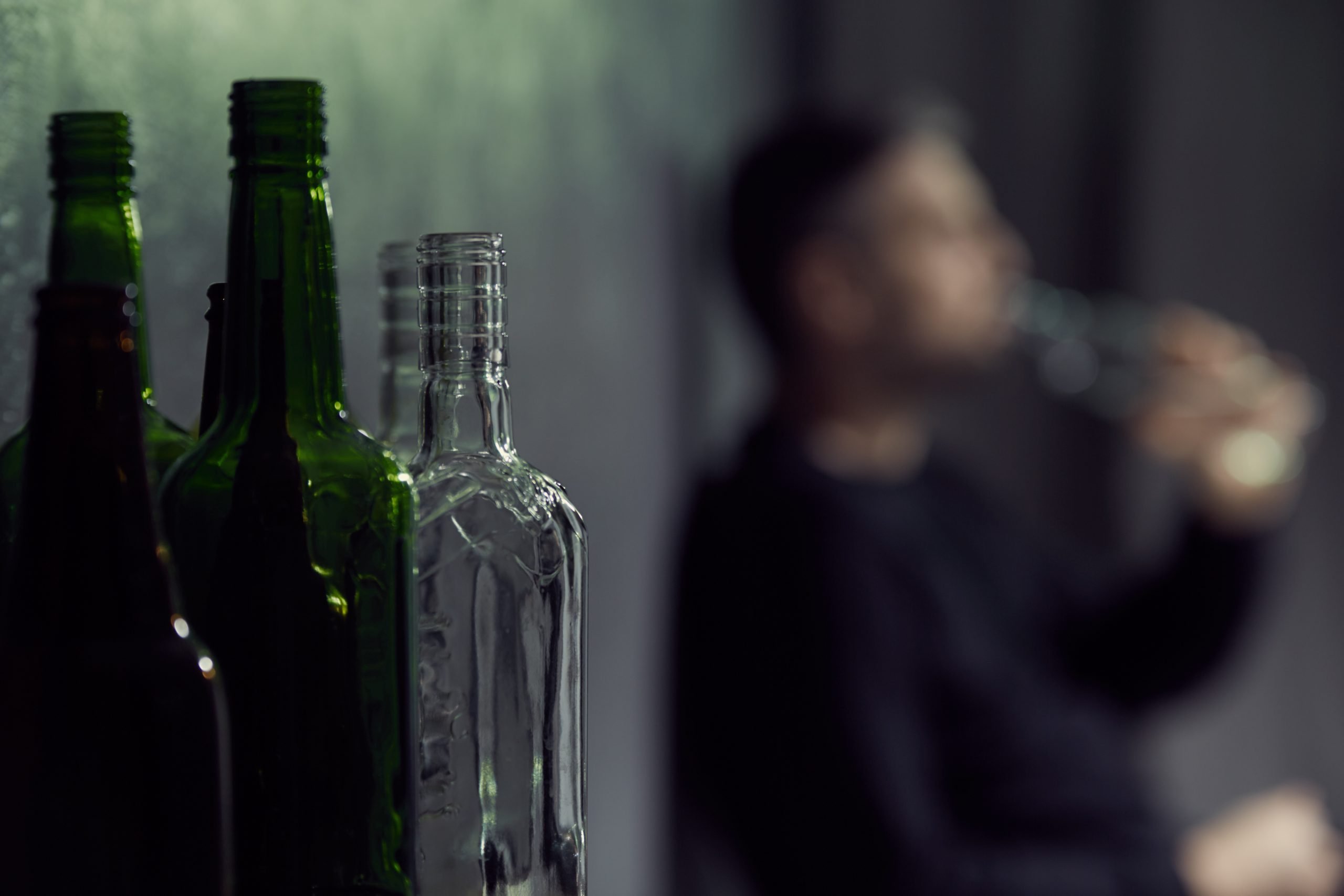 Empty bottles of alcohol with drinking man