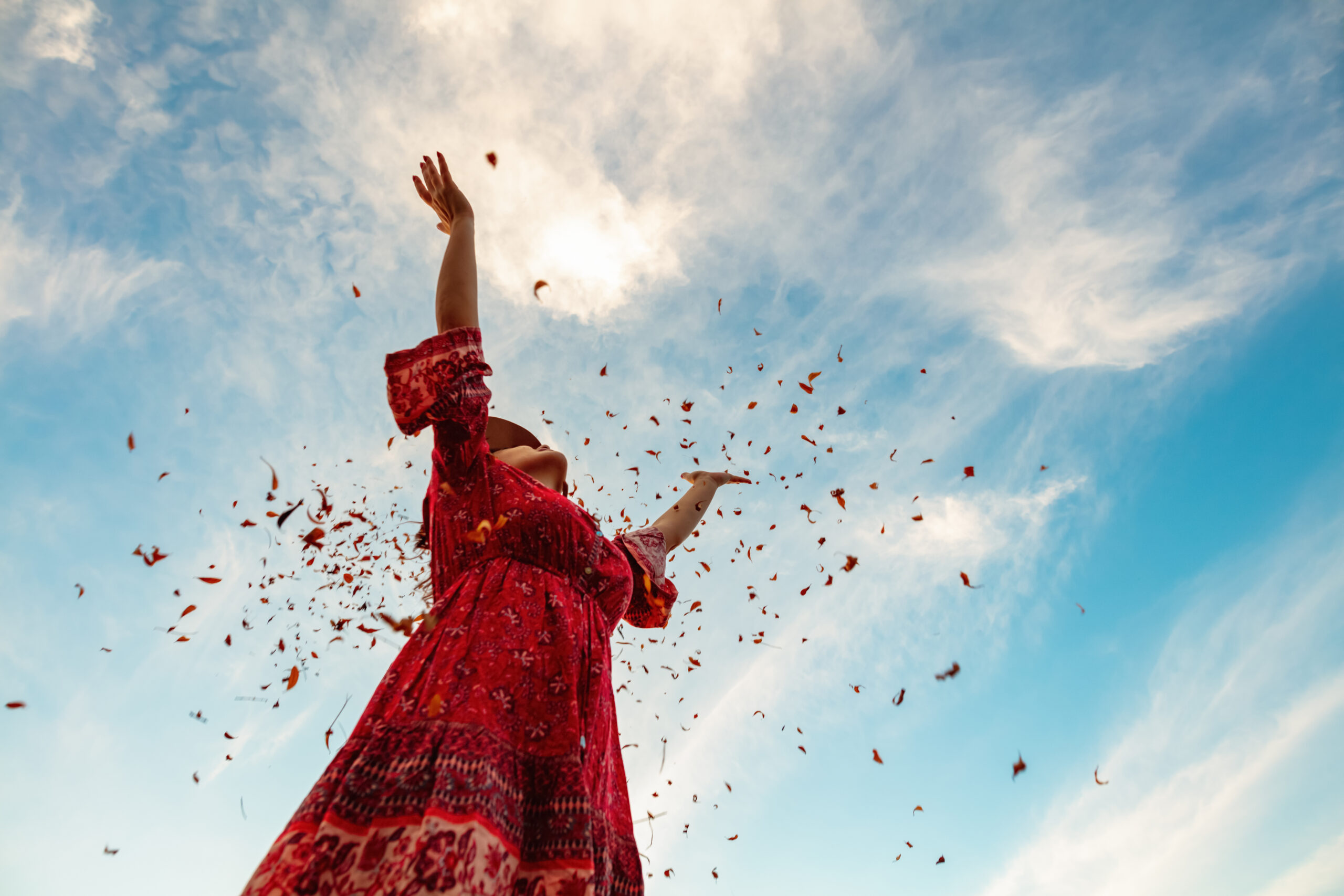 Cheerful Young Female With Pleasure Spending Time Outdoors. Throwing Up Dry Tree Leaves in the Sky. Enjoying Warm Autumn Day in the Park.