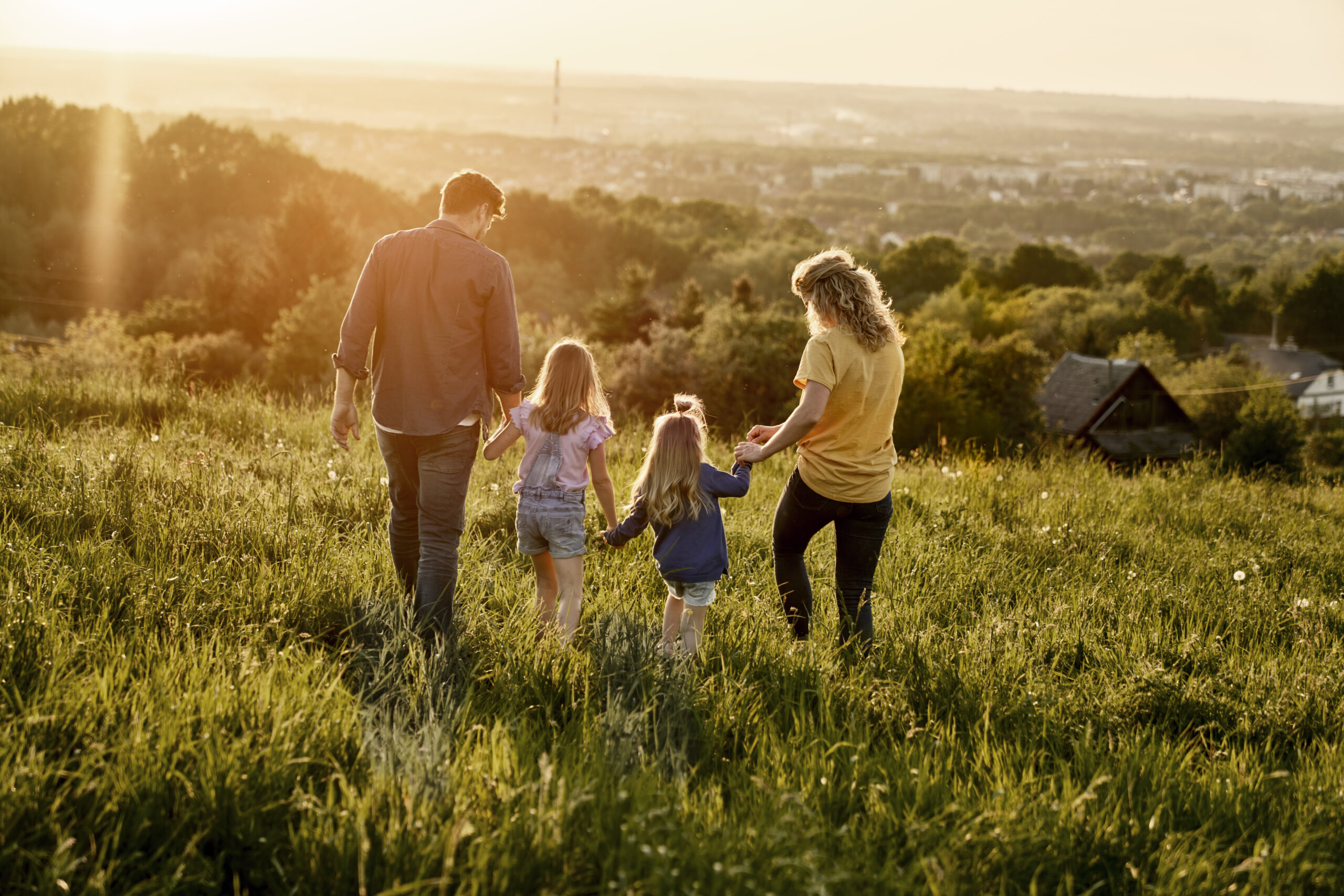 Rear view of family with two daughters walking at the meadow