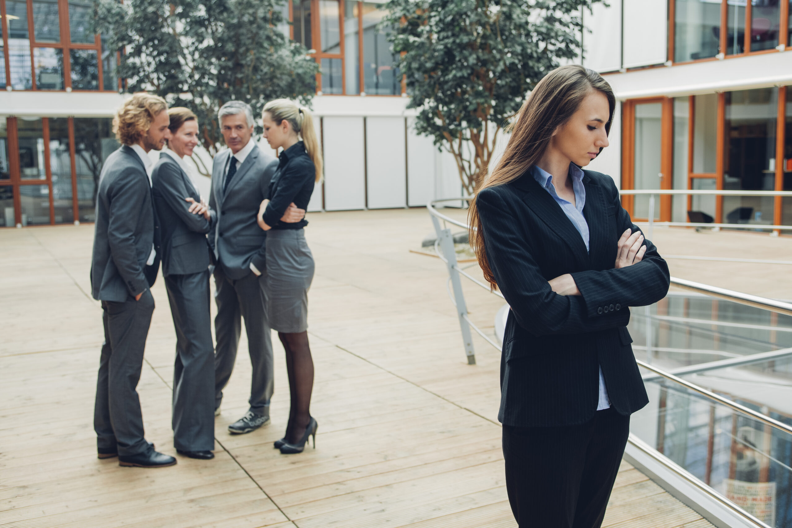 Businesswoman with crossed arms, excluded from group of business people