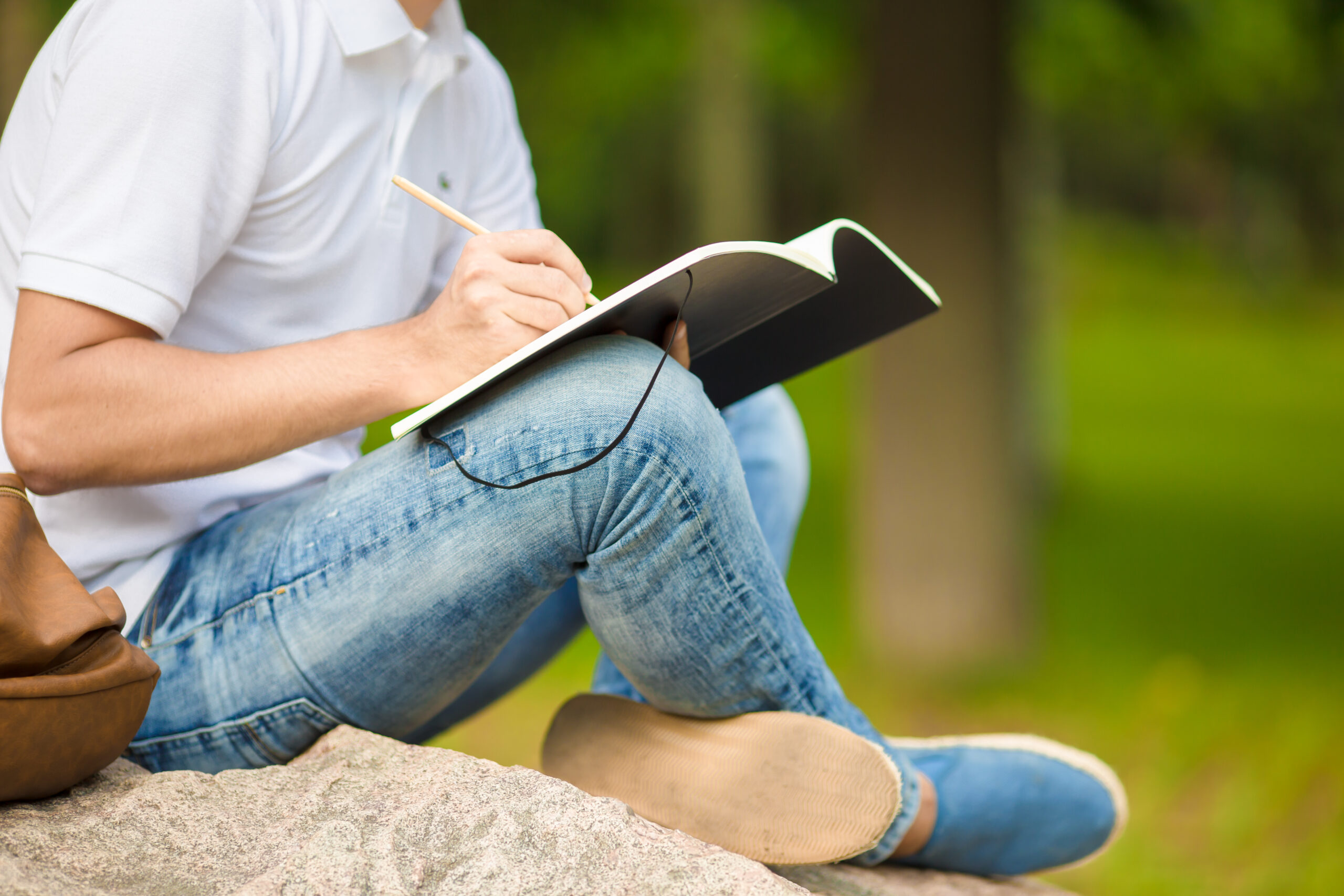 Close-up of hands of boy studying for college exam in park outside