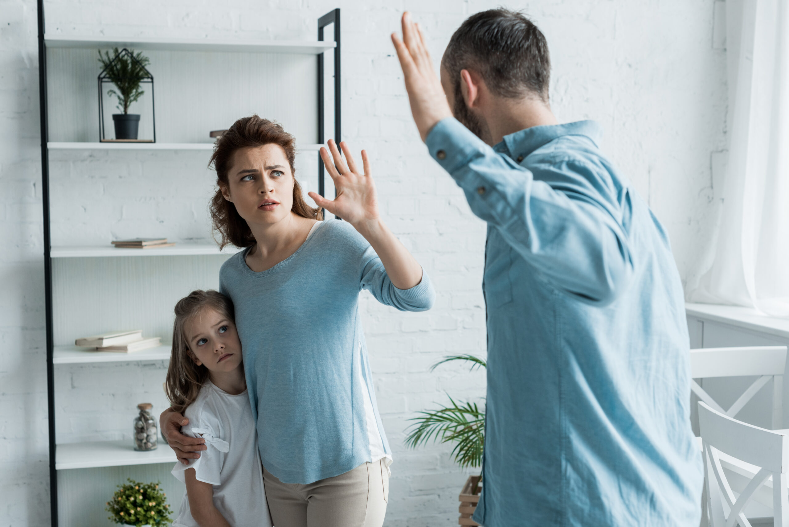 selective focus of scared mother gesturing while looking at angry husband at home