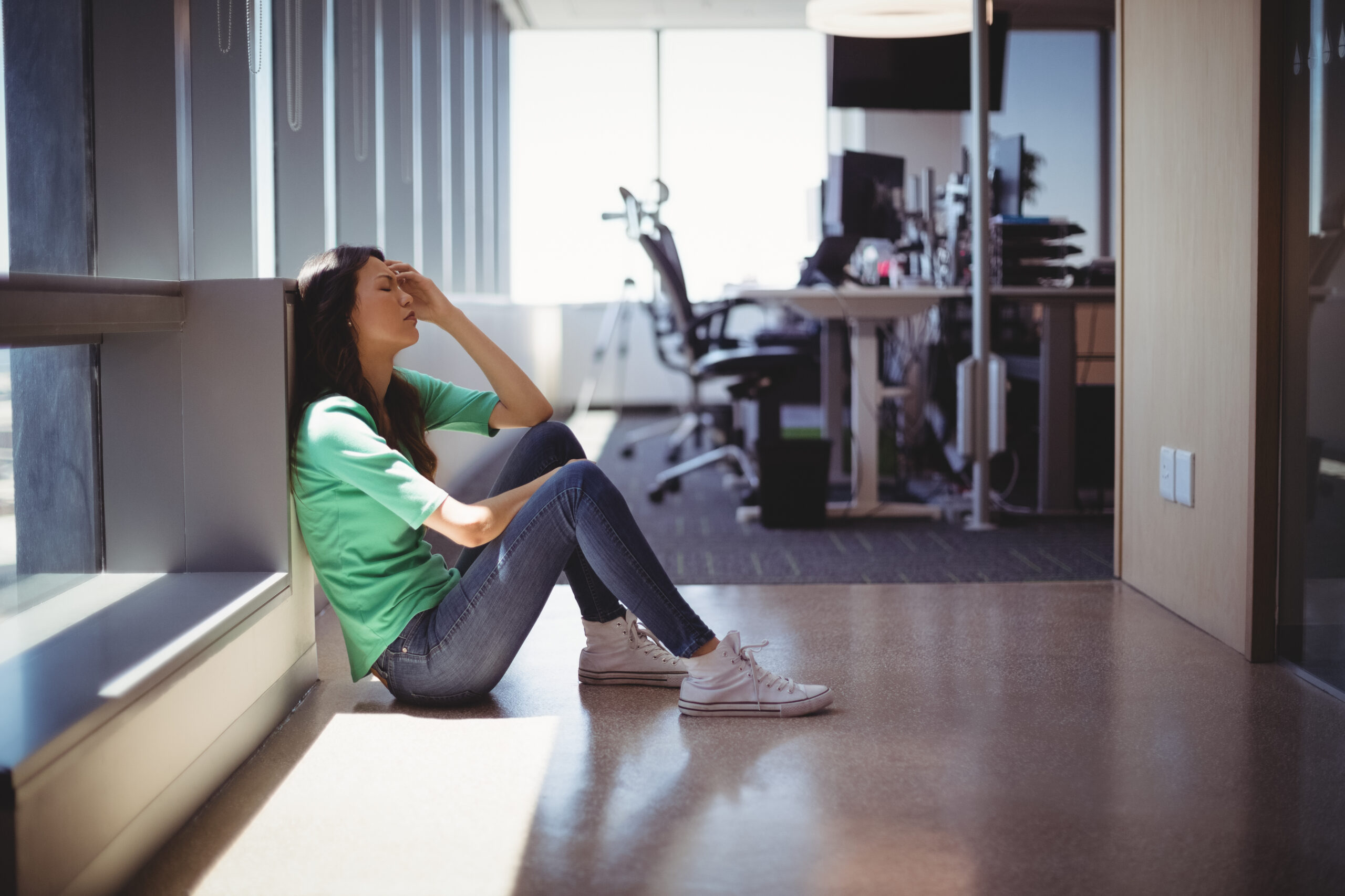 Worried female executive sitting in corridor at office