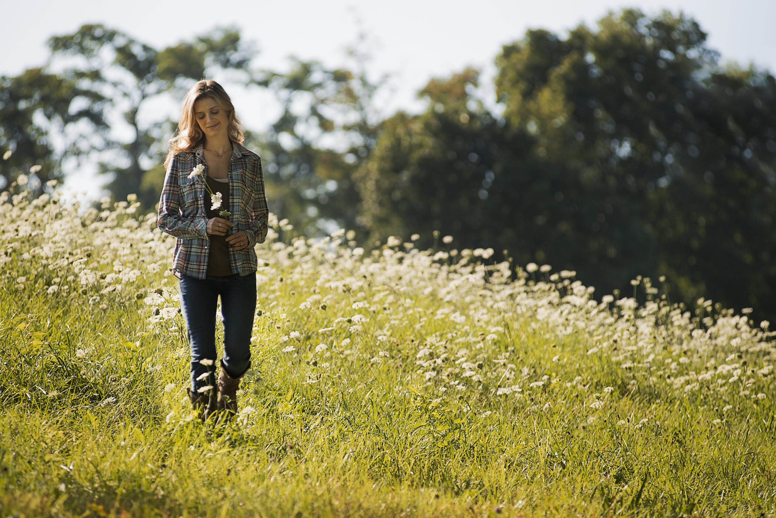 A young woman walking in a wild flower meadow.