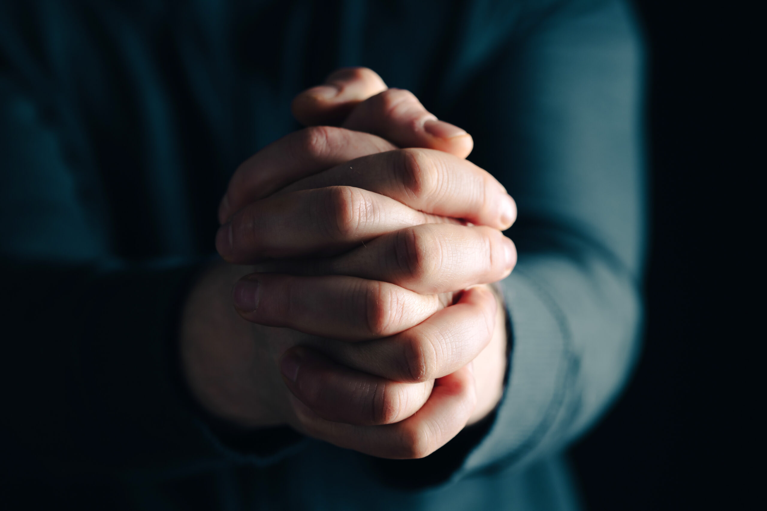 Praying hands with faith in religion and belief in God on dark background. Power of hope or love and devotion.