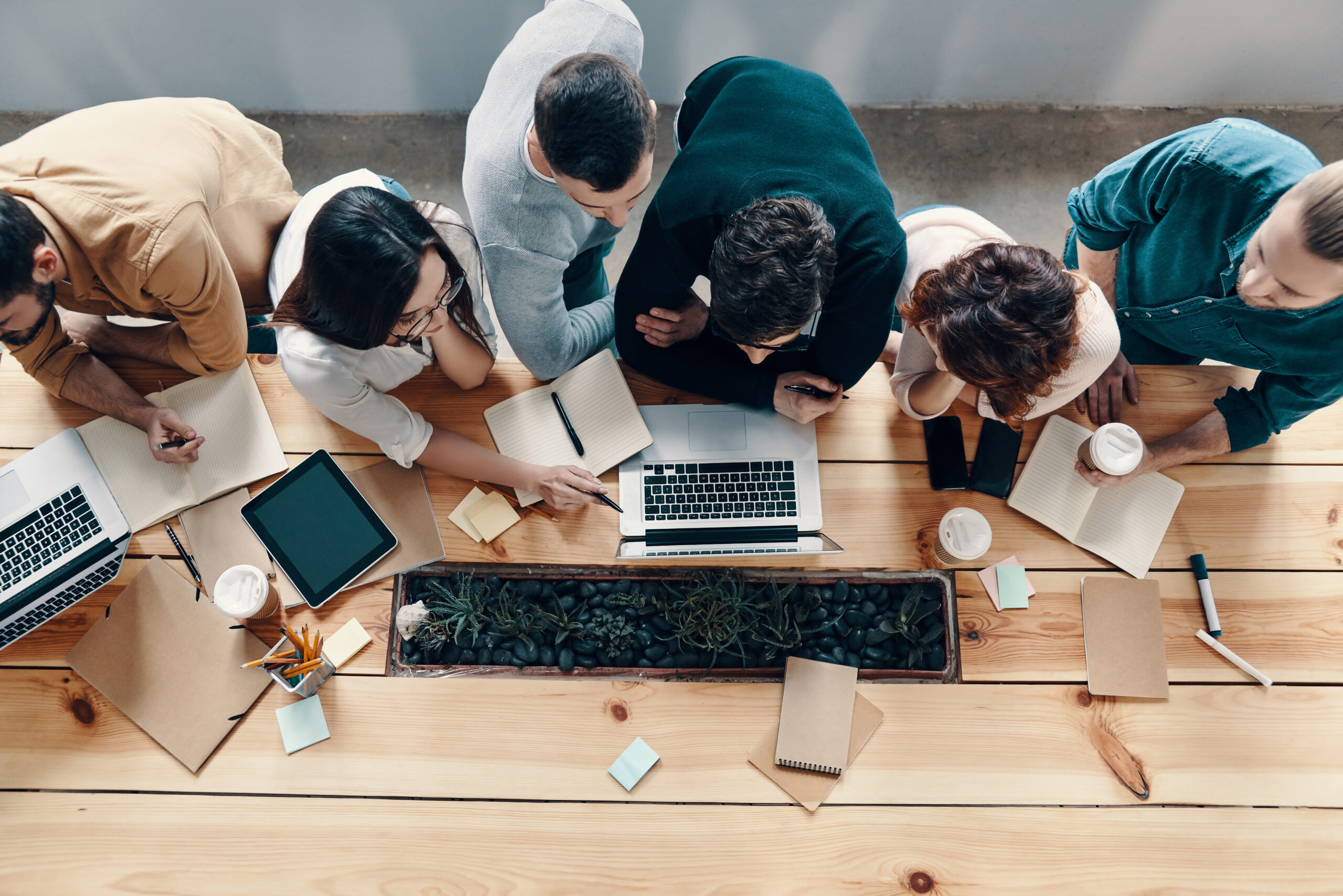 Teamwork. Top view of young modern people in smart casual wear using modern technologies while working in the creative office