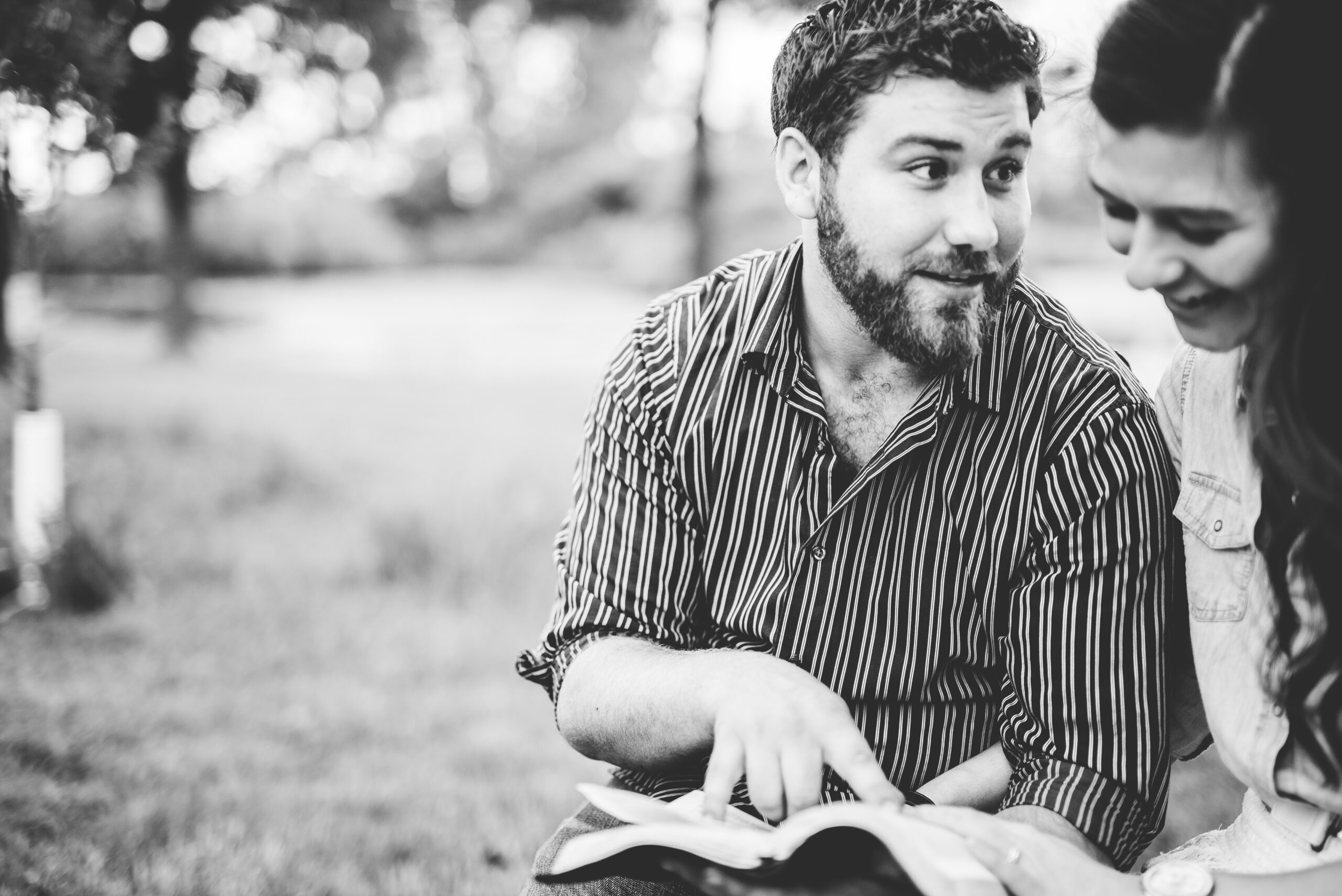 A grayscale shot of a young Christian couple studying the bible on a blurred background