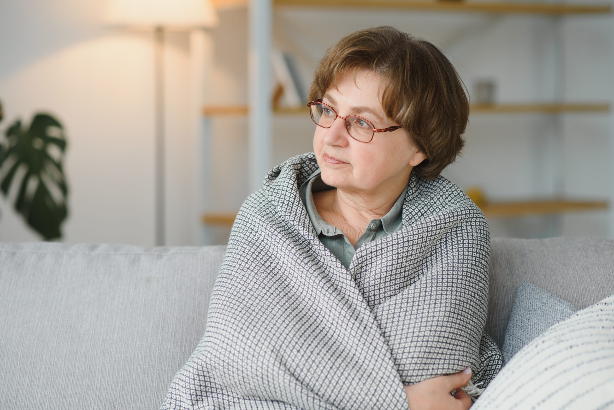 Pensive thoughtful middle aged lady looking away sit alone at home feel anxious lonely, sad depressed melancholic old mature woman suffer from sorrow grief thinking of problem suffer from solitude