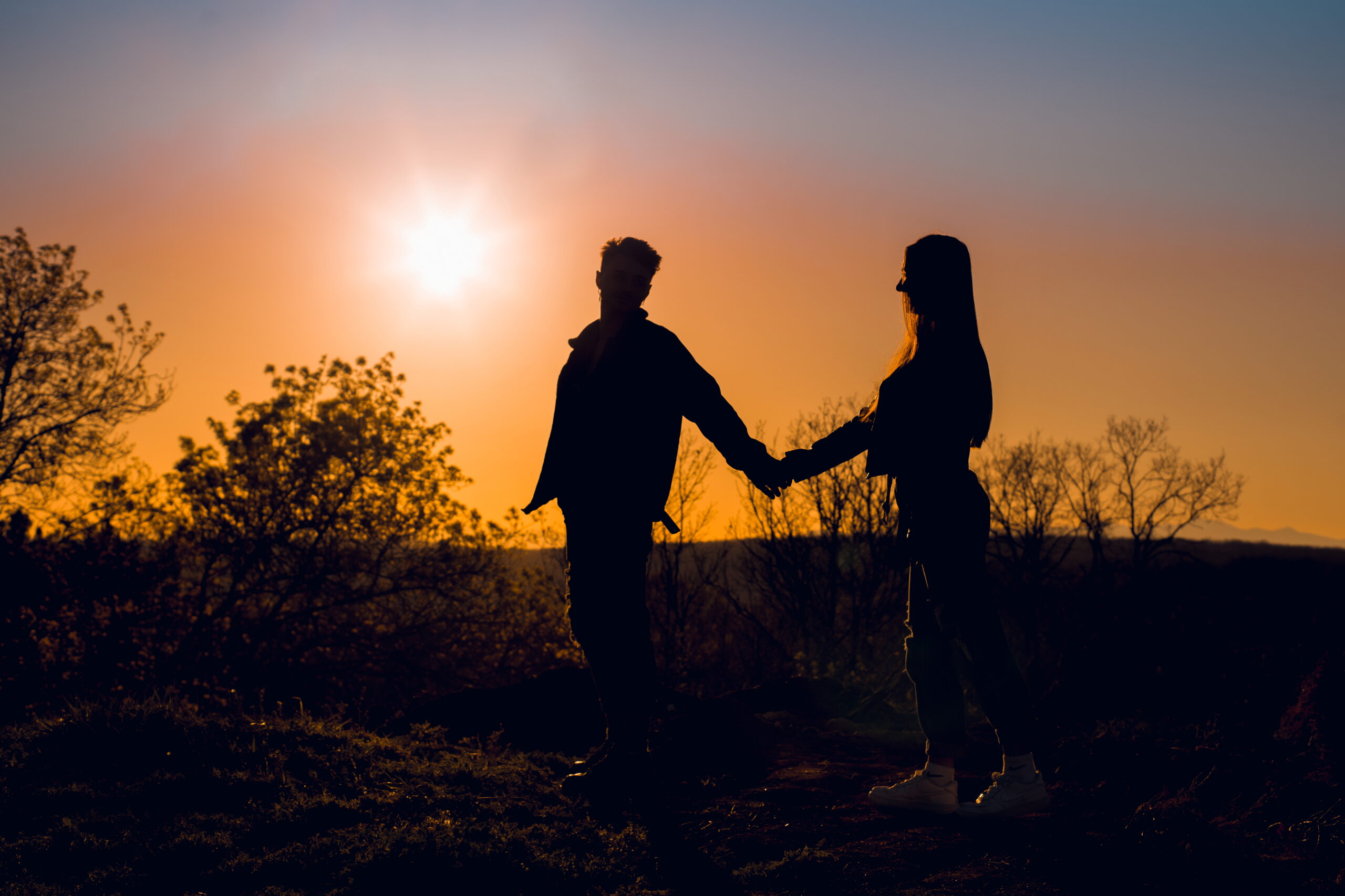 Silhouette of couple holding hands at sunset