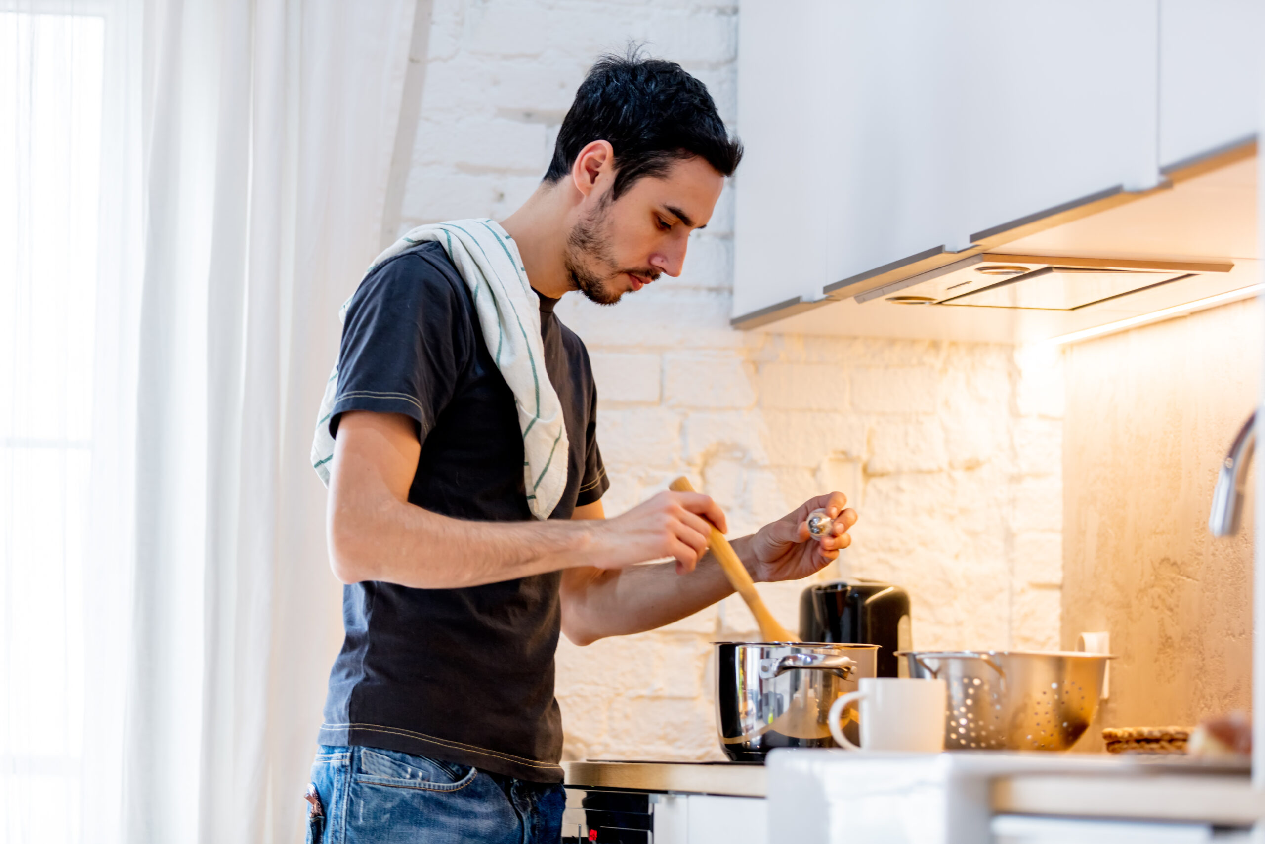 Young man in black shirt cooking at kitchen in home. candid view