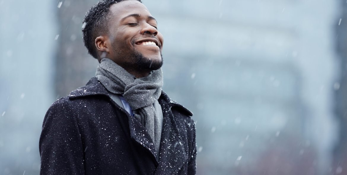 Cheerful man enjoying snowflakes falling from upwards