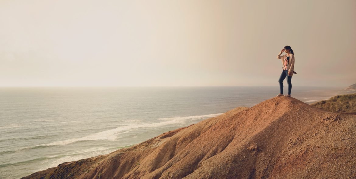Woman on the top of a clif looking to the ocean