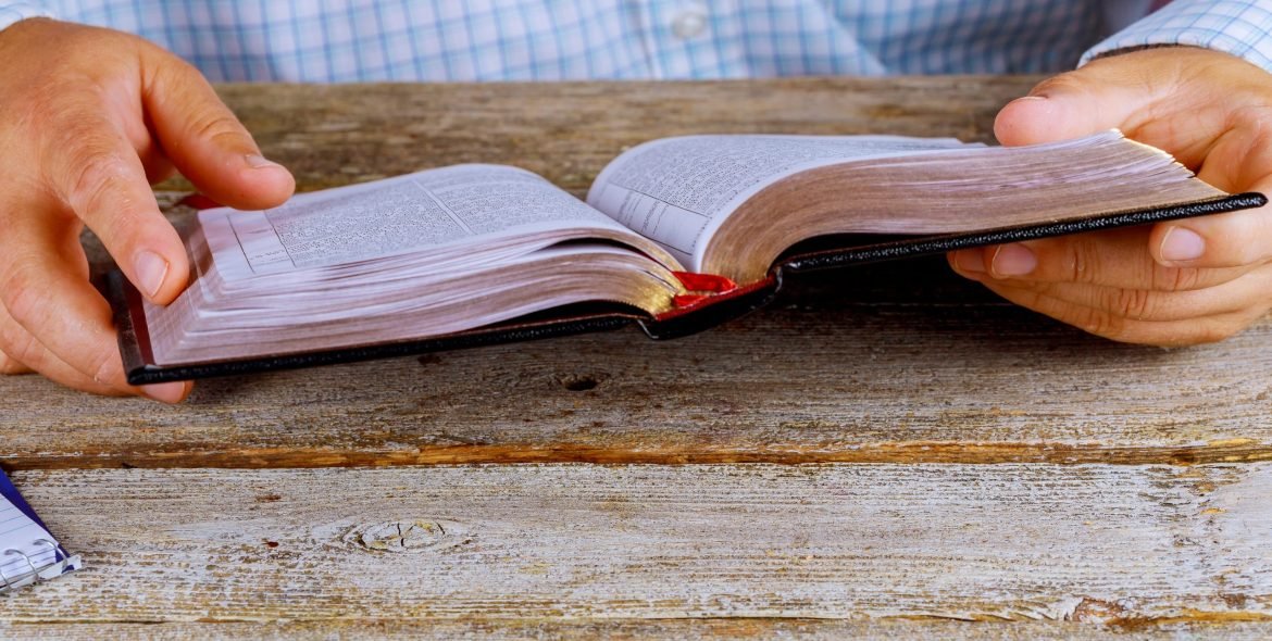 A men sitting reading the Holy Bible close up hands