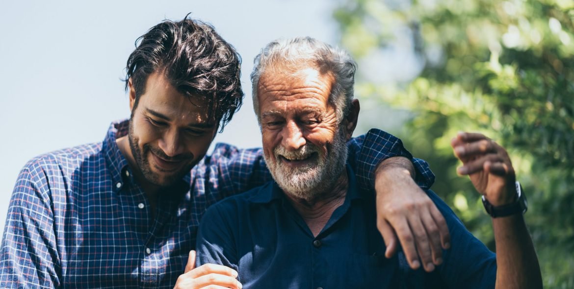 An adult hipster son and senior father at home, talking.