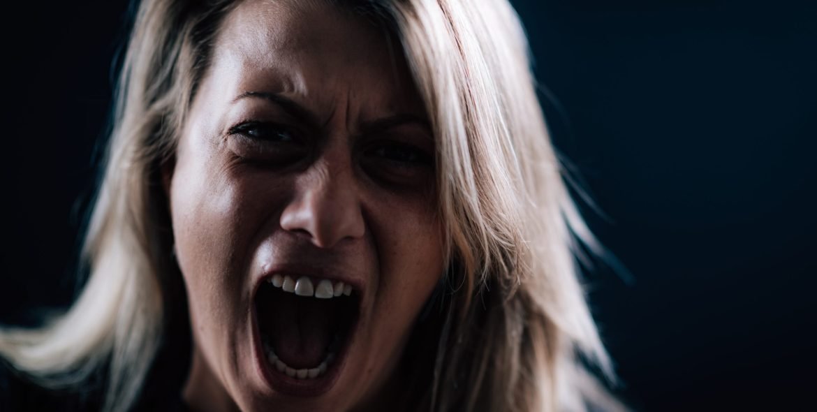 Anger - intense portrait of an angry woman on black background