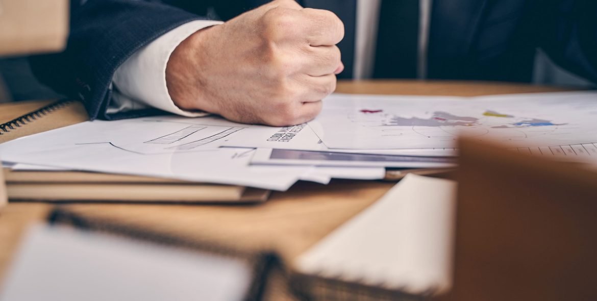 Close up of serious office worker making fist while working at his business plan