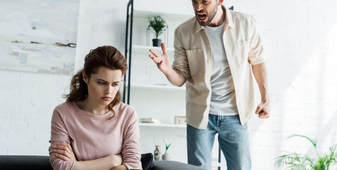angry man screaming near upset woman with crossed arms