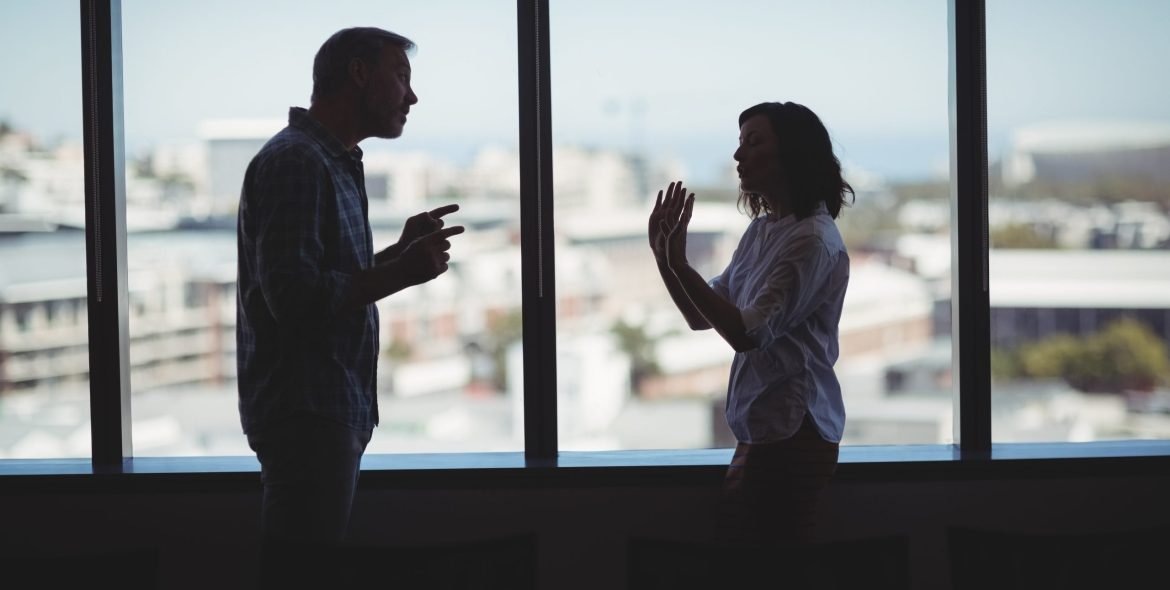Business couple arguing near the window in office