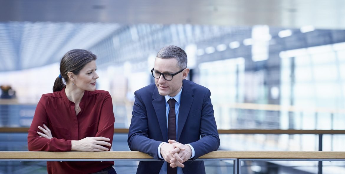 Businesswoman and man talking on office balcony