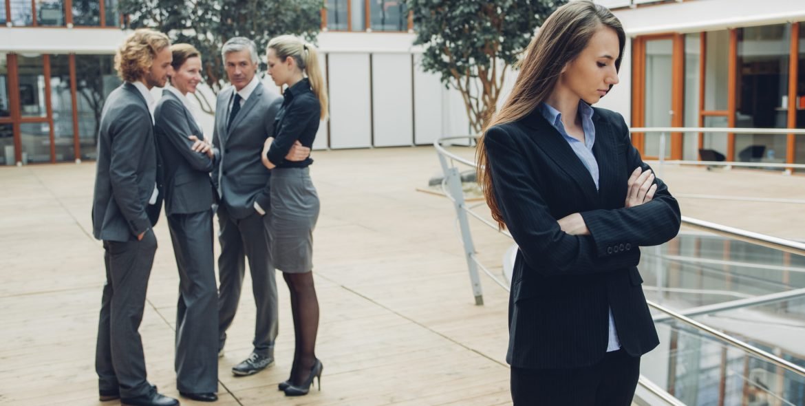 Businesswoman with crossed arms, excluded from group of business people