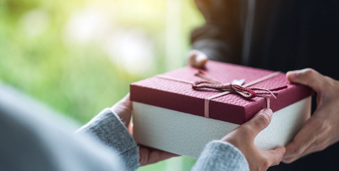 Closeup image of a man giving a woman a gift box