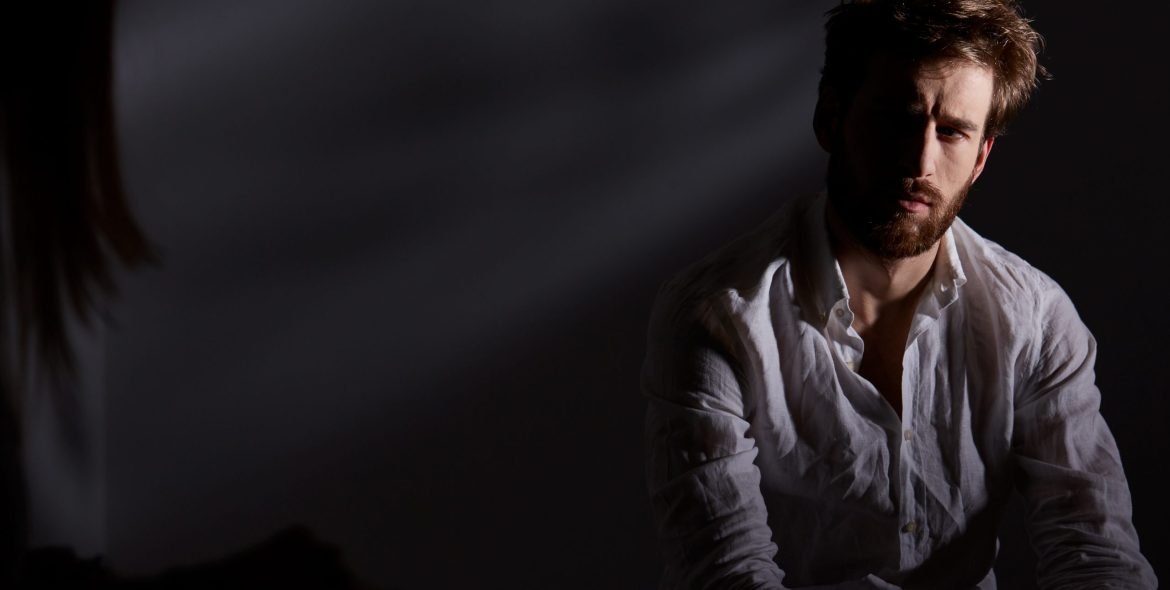 Depressed and thoughtful man sitting alone in dark room