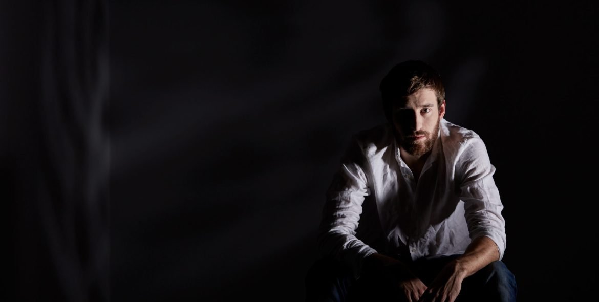 Desperate man sitting alone in dark room