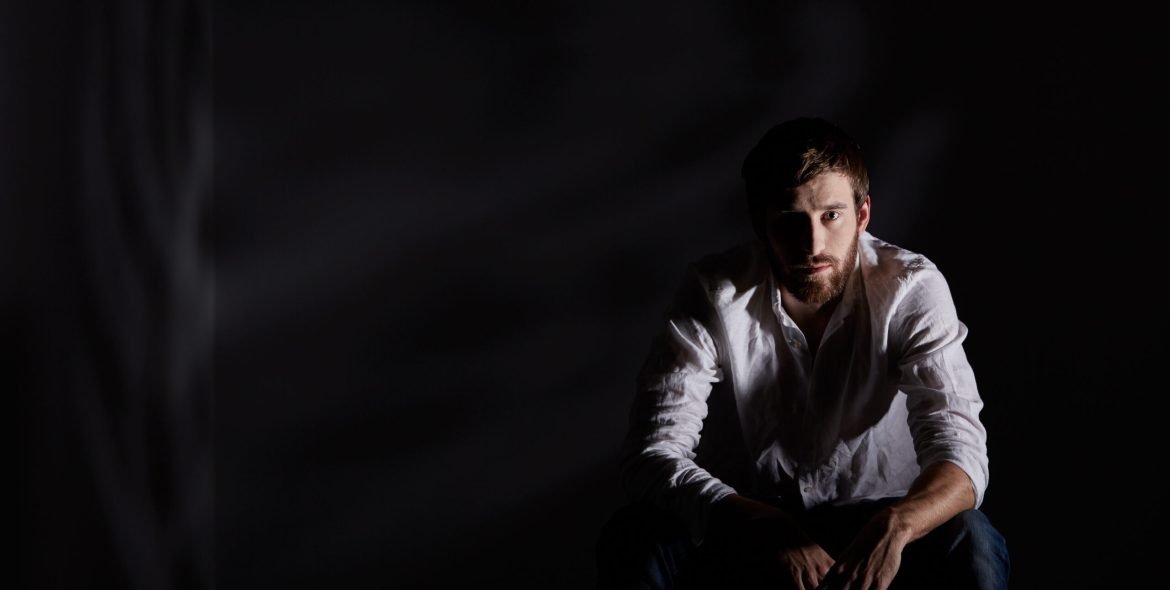 Desperate man sitting alone in dark room