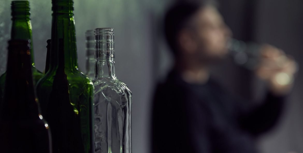 Empty bottles of alcohol with drinking man