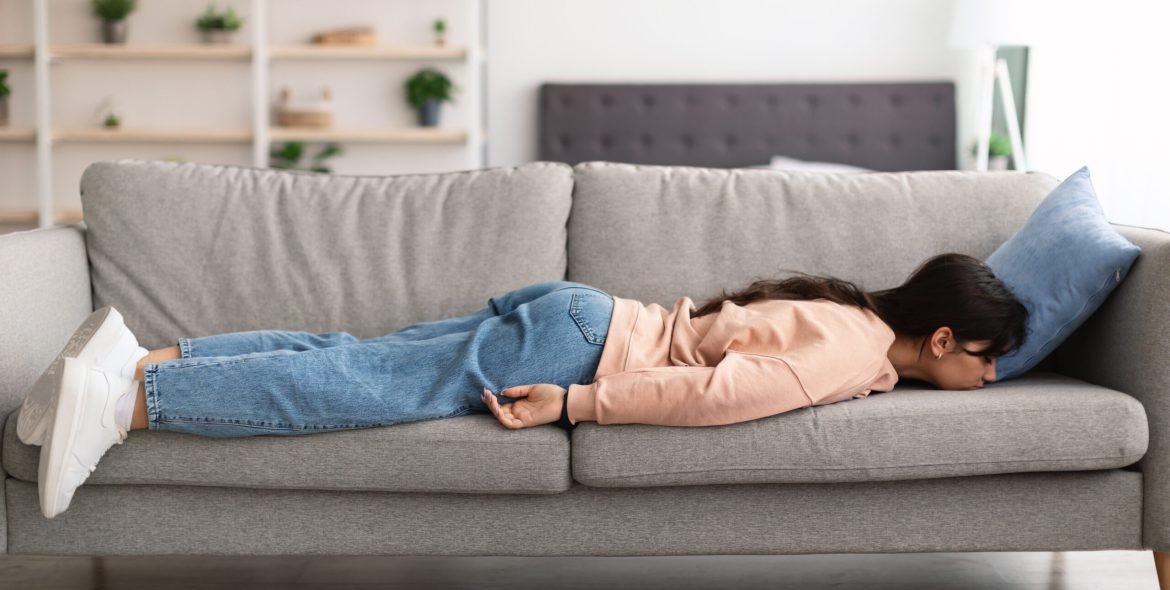 Lack of Energy Concept. Full Body Length Of Exhausted Sleepless Young Woman Lying On The Couch With Face Down, Tired In The End Of Hard Working Day, Fatigued Female Resting At Home