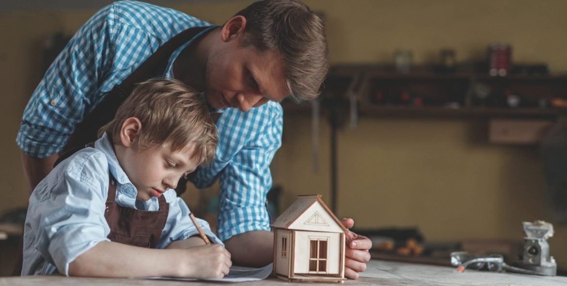 Father and son with a wooden house in the workshop