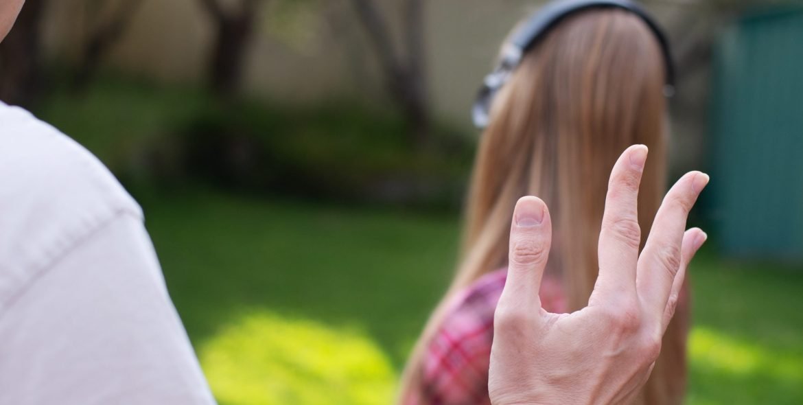 Problems between generations concept. Father argue with teenage daughter who is ignoring him. She wearing headphones and turned apart from him.