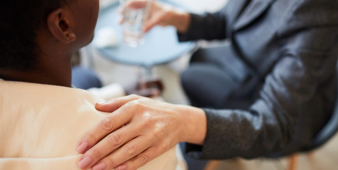 Close up of female psychologist comforting African-American teenager during therapy session, copy space