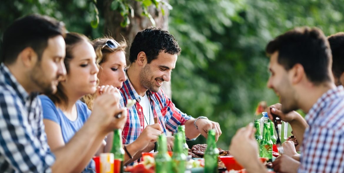 Friends eating outdoors and having fun after barbecuing