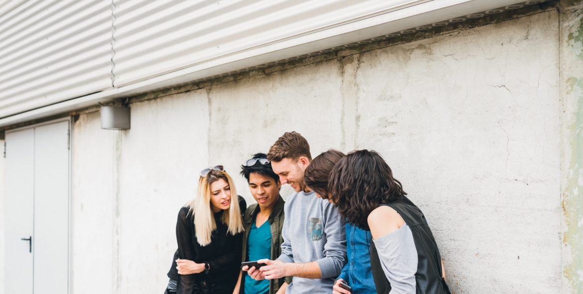 Group of multiethnic friends millennials using smartphone addicted to technology trends following and chatting  and watching videos