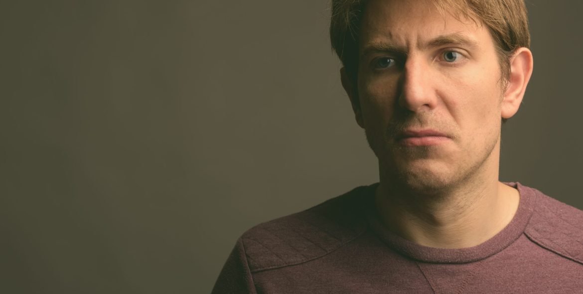 Studio shot of handsome man wearing purple long sleeved shirt against gray background