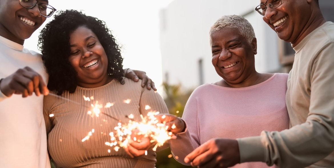 Happy African family celebrating with sparklers fireworks at house party - Parents unity and holidays concept