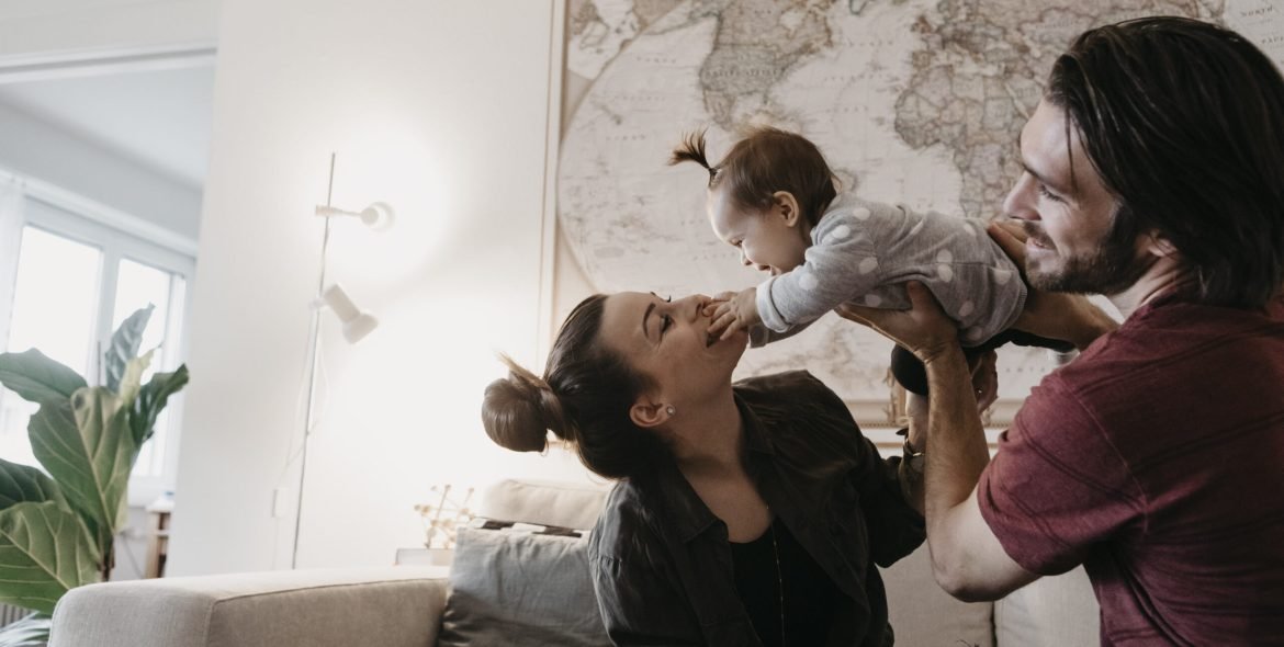 Happy family playing with baby girl in living room at home