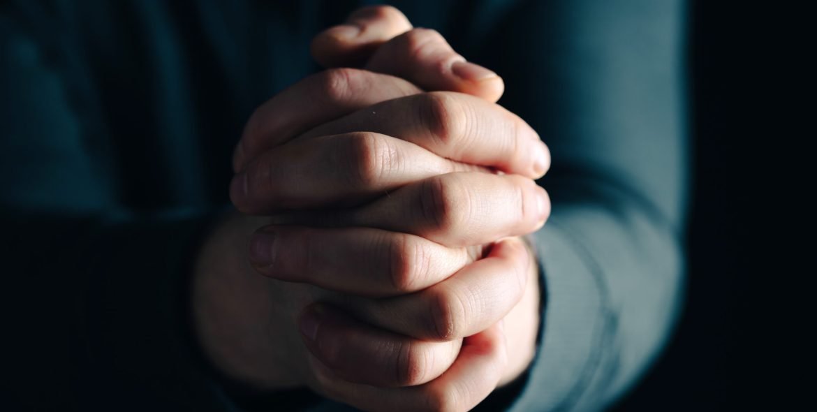 Praying hands with faith in religion and belief in God on dark background. Power of hope or love and devotion.