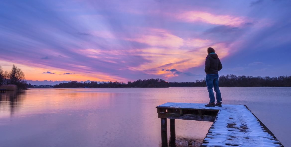 Man overthinking problems on pier during beautiful sunset in winter