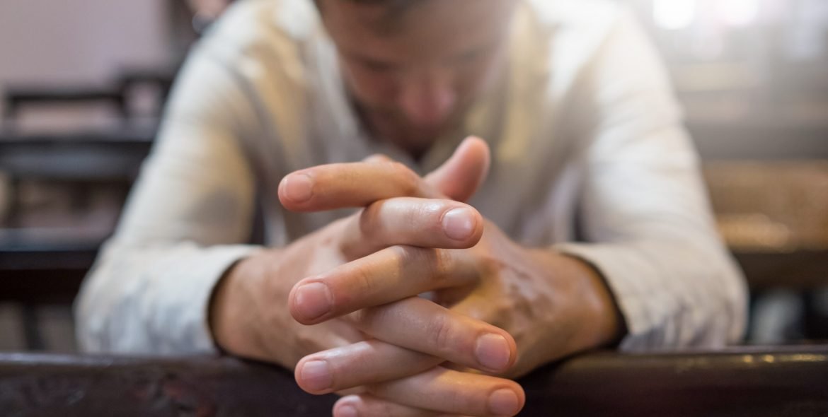 caucasian man praying in church. He has problems and ask God for help. Concept of religion faith